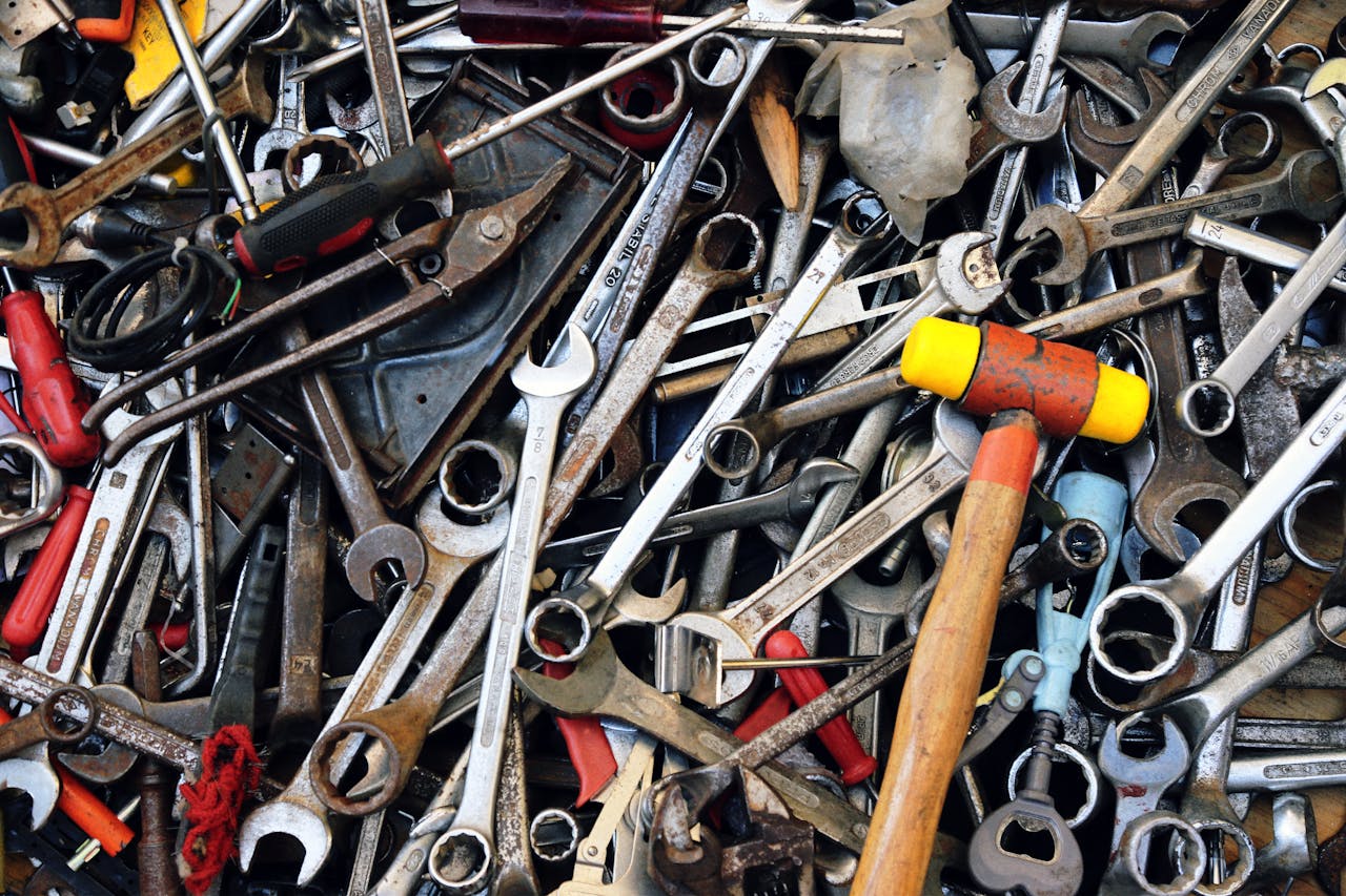 Close-up view of various tools including wrenches and a hammer, providing a cluttered yet organized look.